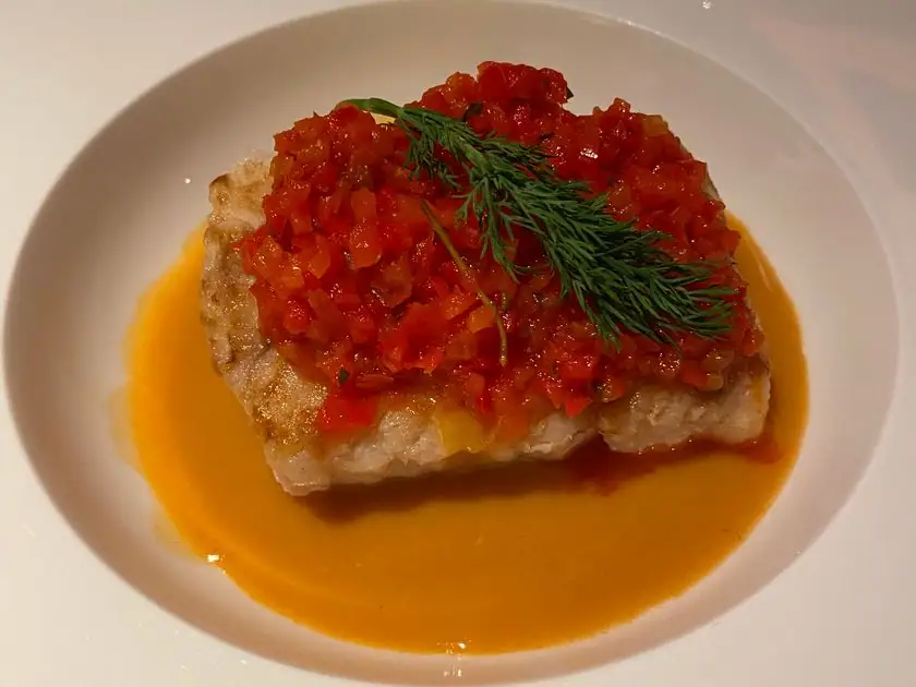 Fischfilet mit Tomatenconcassé und Dill auf weißem Teller in der Swiss First Class