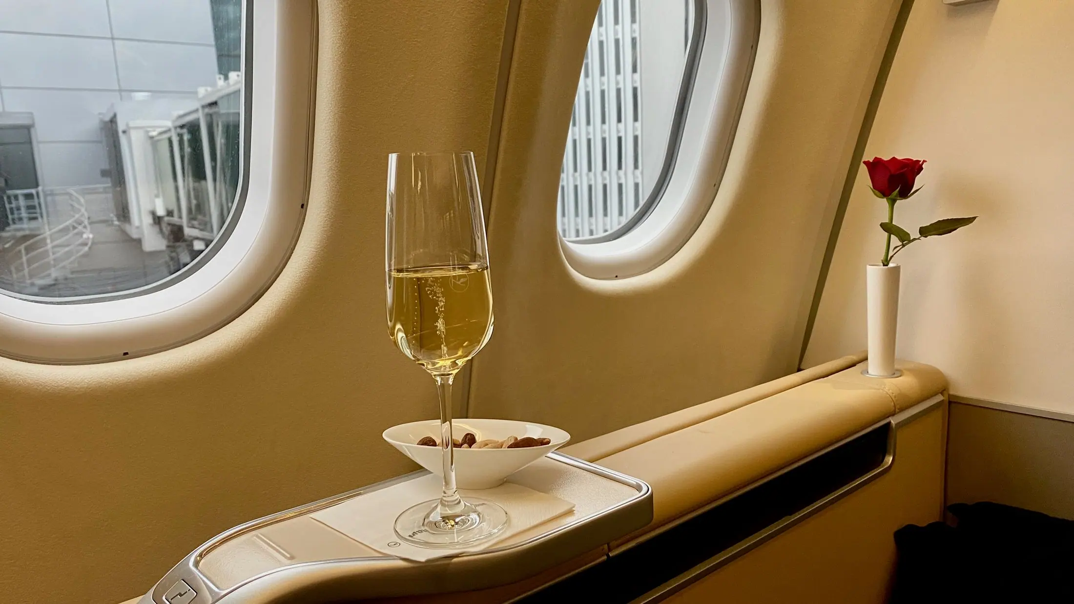Ein Glas Champagner und eine rote Rose auf der Fensterablage einer Lufthansa First Class Suite