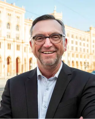 Christoph Pfeiffer lächelnd vor einem Münchner Gebäude